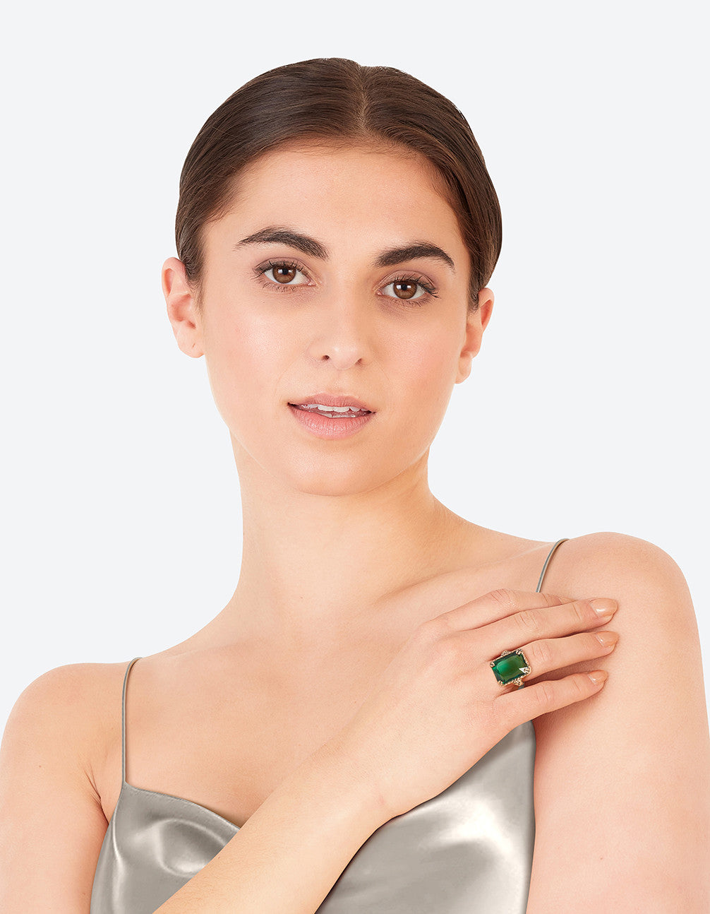 Featuring an emerald square cut stone on gold band with ornate prong setting on finger view
