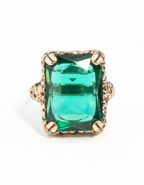 Highlighting an emerald square cut stone on gold band with faceted gem detail close up view