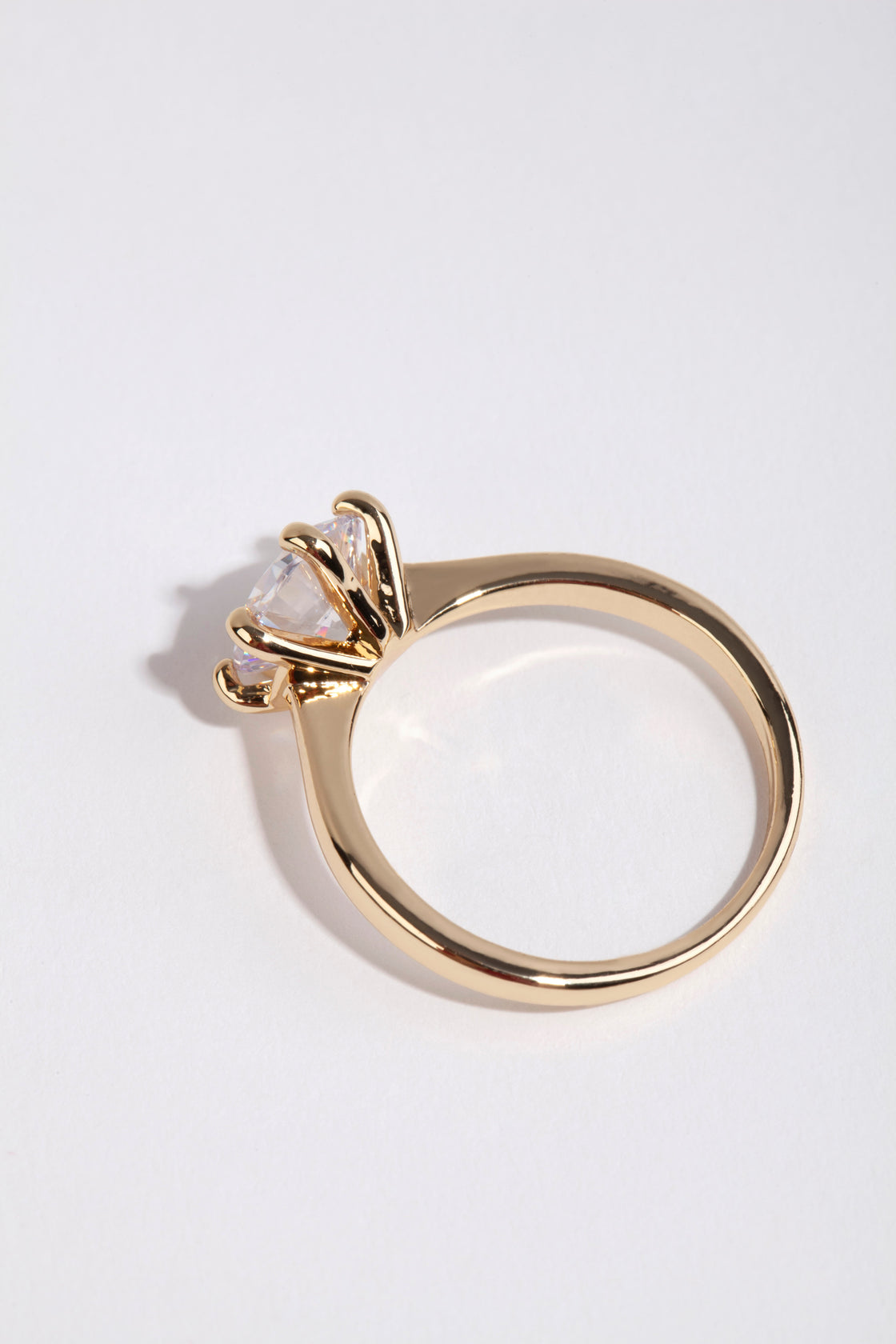 Crafted from gold plated material this round cubic zirconia ring highlights clear stone detailing side detail view