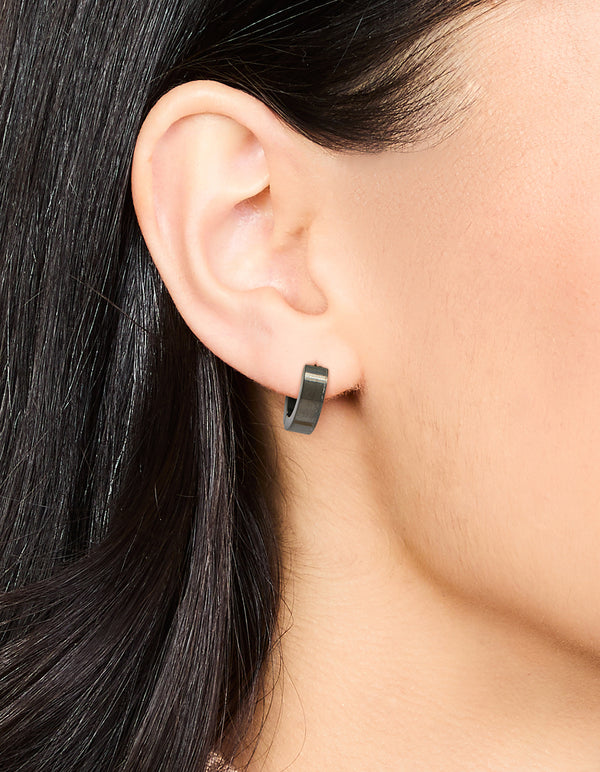 Showcasing waterproof black coated stainless steel wide huggie earrings on ear view