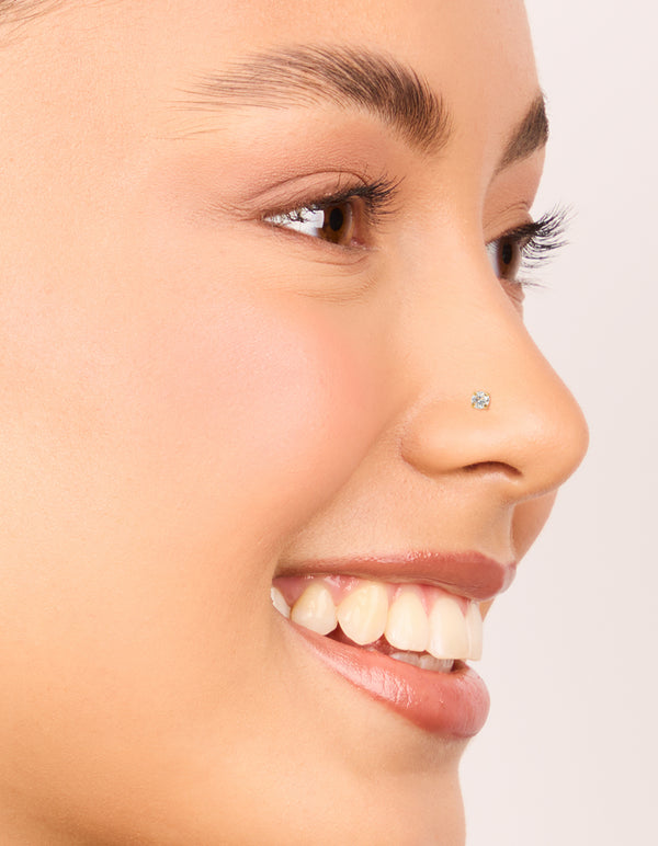 Highlighting gold plated titanium cubic zirconia nose studs worn on nostril featuring hoop closure nose view