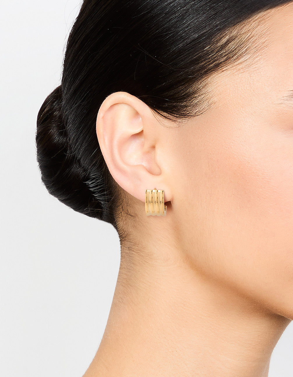 Crafted from waterproof gold plated stainless steel, ribbed huggie earrings on ear view