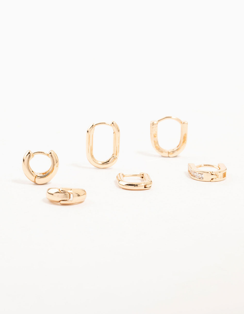 Showcasing gold cubic zirconia oval huggie earrings in a 3-pack featuring mixed designs front view