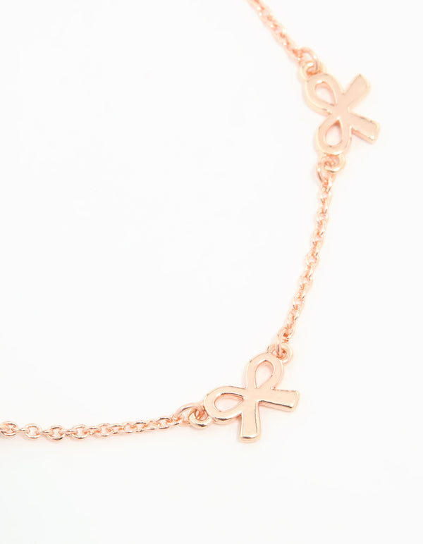 Beautifully crafted rose gold plated sterling silver bracelet featuring dainty bow charm accents close up view