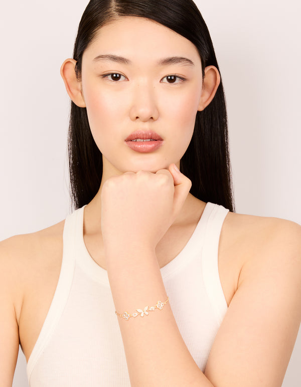 Elegant gold cubic zirconia butterfly and flower toggle bracelet in white on model view