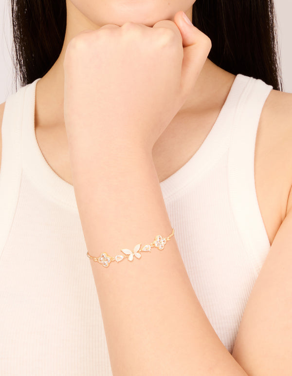 Showcasing a gold cubic zirconia butterfly and flower toggle bracelet in white on wrist view