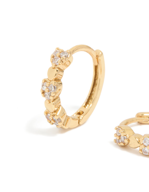 Showcasing mini heart huggie earrings with cubic zirconia stones in gold plated finish close up view