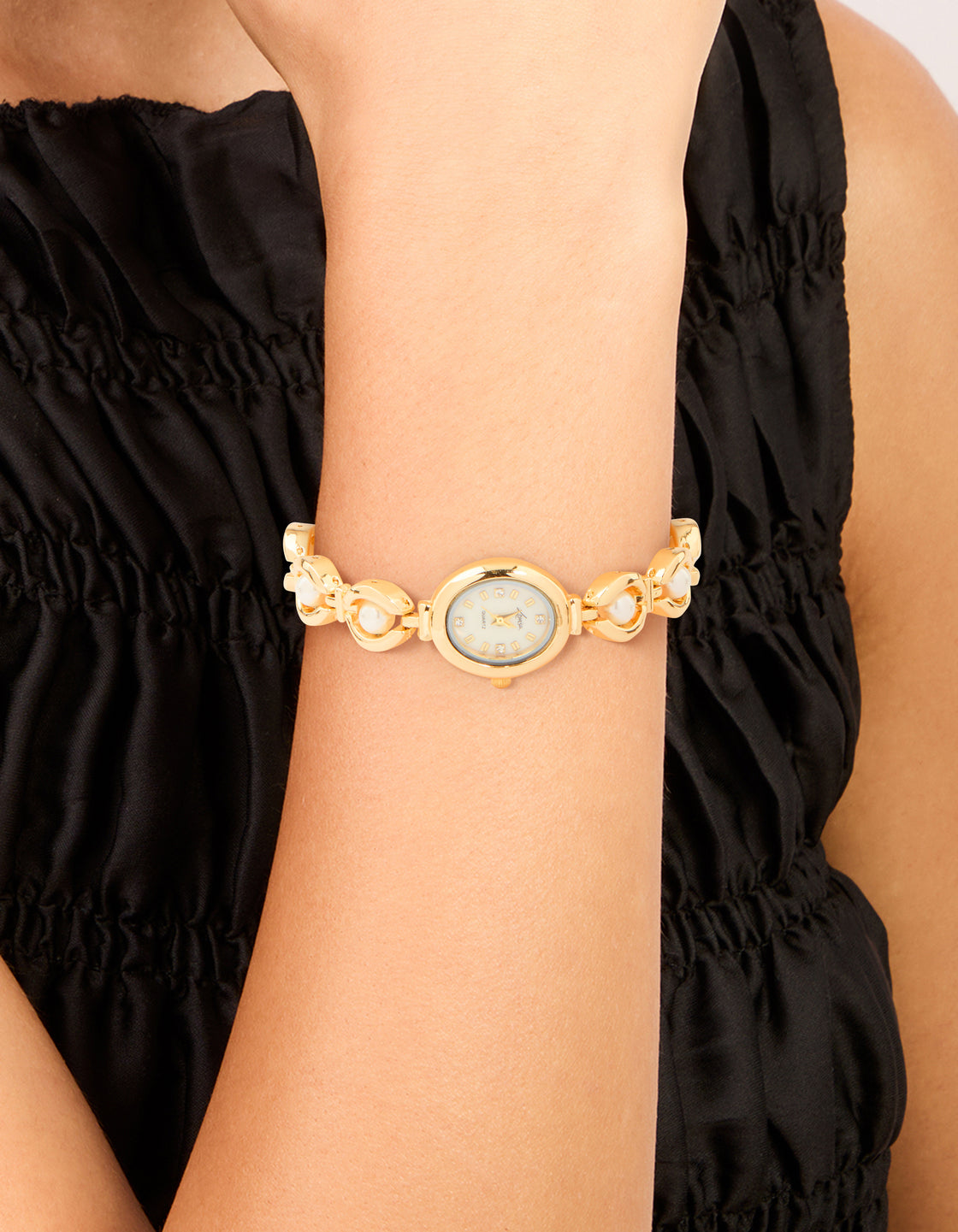 Showcasing a pearl embellished charm watch featuring white dial with numbers, casual occasion styling, analog movement, women's link-band bracelet in gold on wrist view