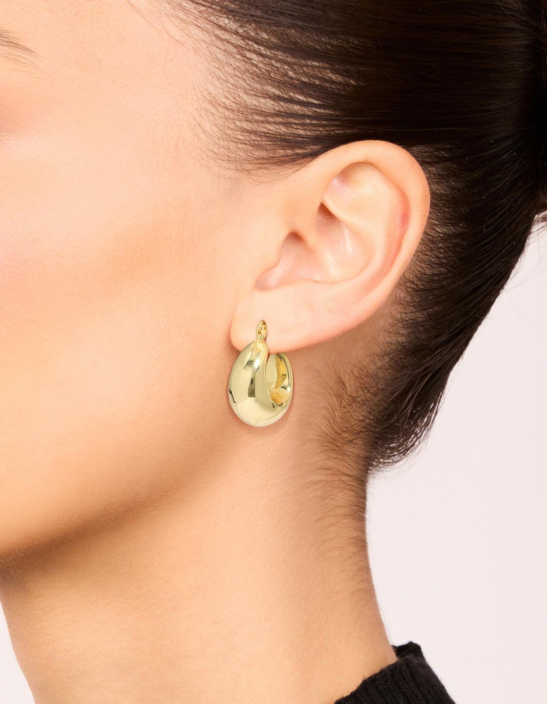 Featuring gold plated brass medium huggie earrings worn on ear view