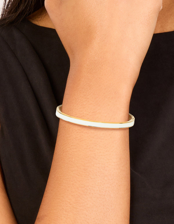 Featuring a waterproof gold plated stainless steel white enamel hinged bangle in dainty style on wrist view