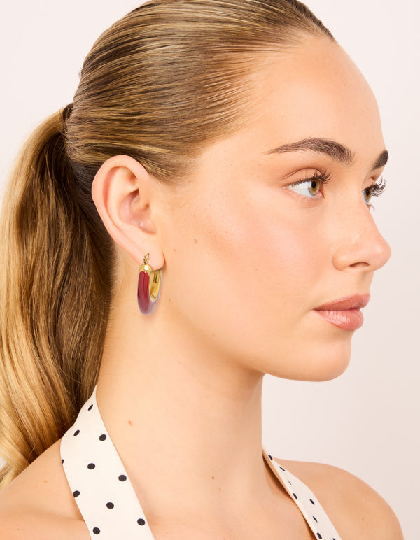 Designed with waterproof statement hoop earrings in stainless steel with crimson enamel and gold plated finish on model view