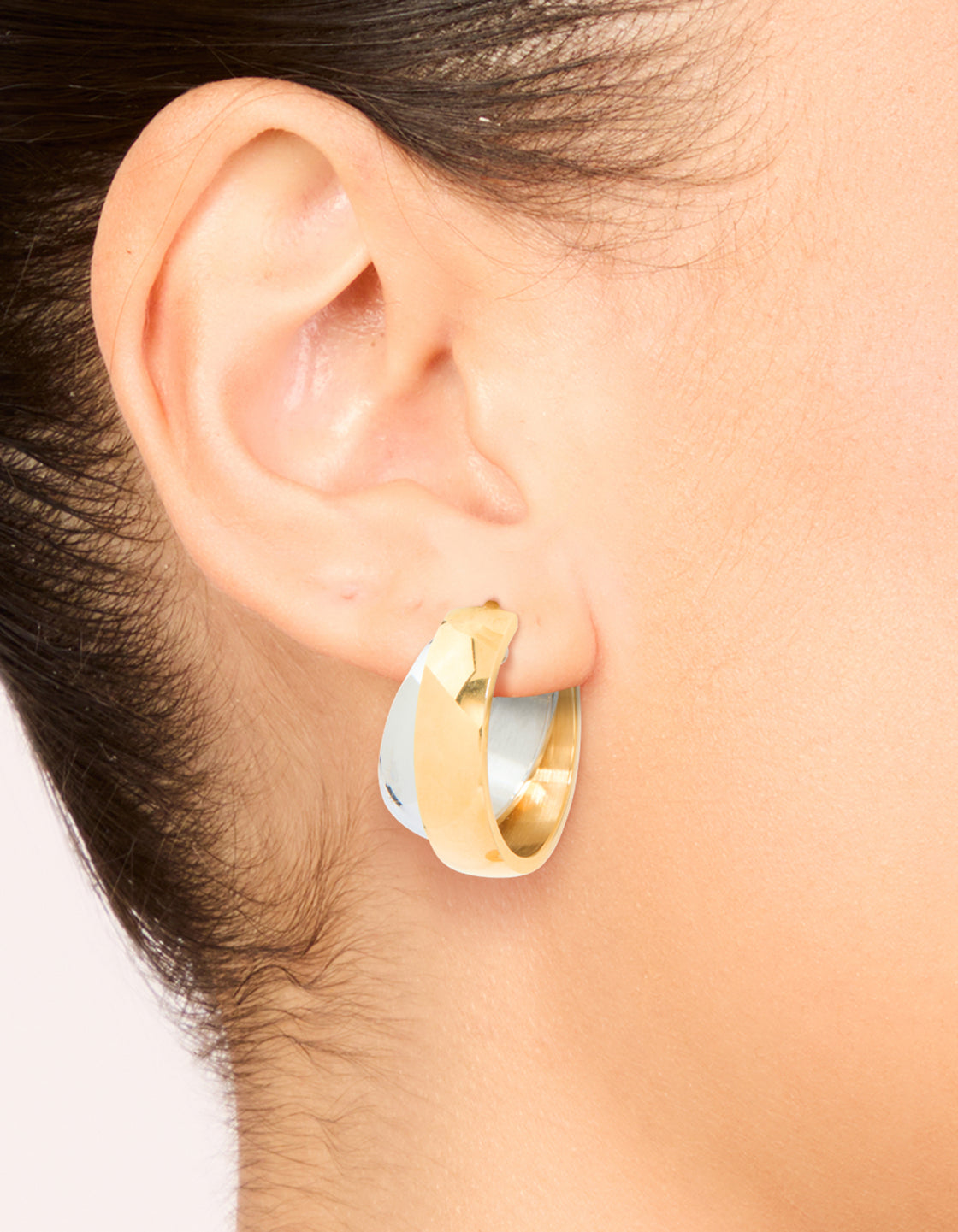 Featuring waterproof mixed metals plated stainless steel small illusion hoop earrings in gold and silver on ear view
