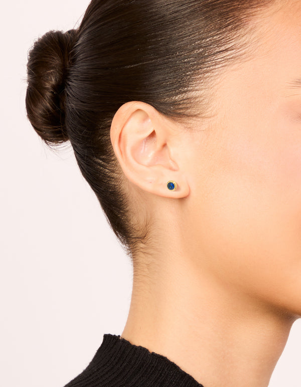 Showcasing waterproof gold plated stainless steel sapphire cubic zirconia September birthstone bezel set stud earrings in dainty style on ear view