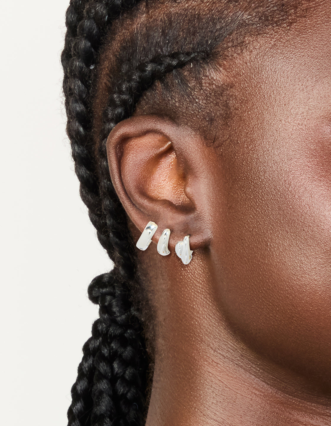 Featuring waterproof stainless steel chunky huggie earrings in silver finish, available as a pack of 3 on ear view