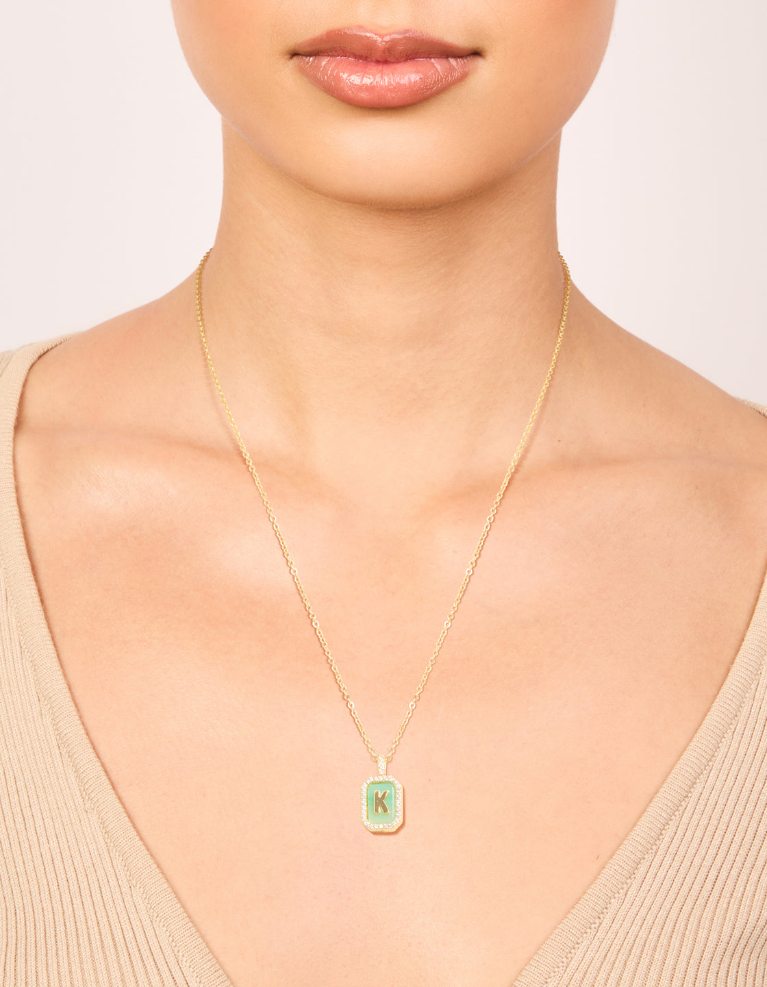 Showcasing a gold plated brass cubic zirconia letter K tag necklace with initials featuring pendant on neck view