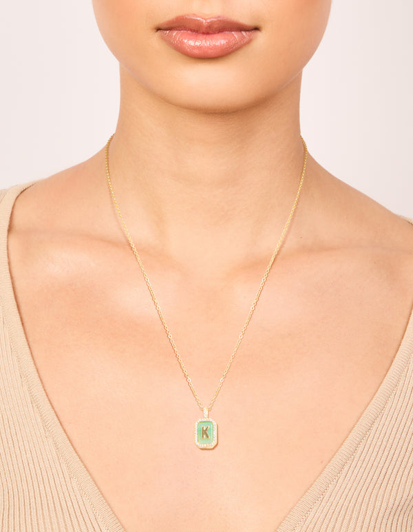 Showcasing a gold plated brass cubic zirconia letter K tag necklace with initials featuring pendant on neck view
