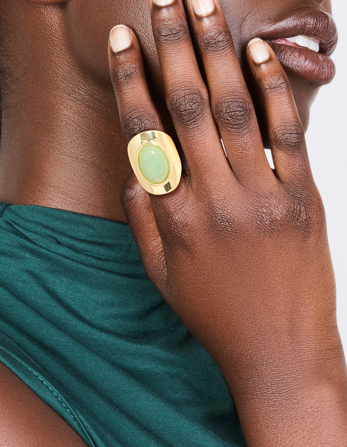 Featuring a gold plated oval green semi precious stone ring on finger view
