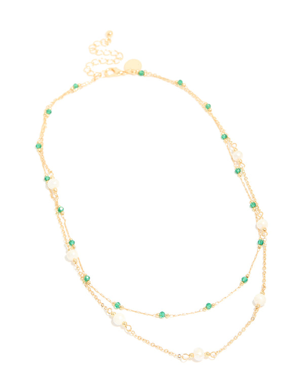 Showcasing a gold plated layered necklace with beads, emerald stone and pearl accents front view