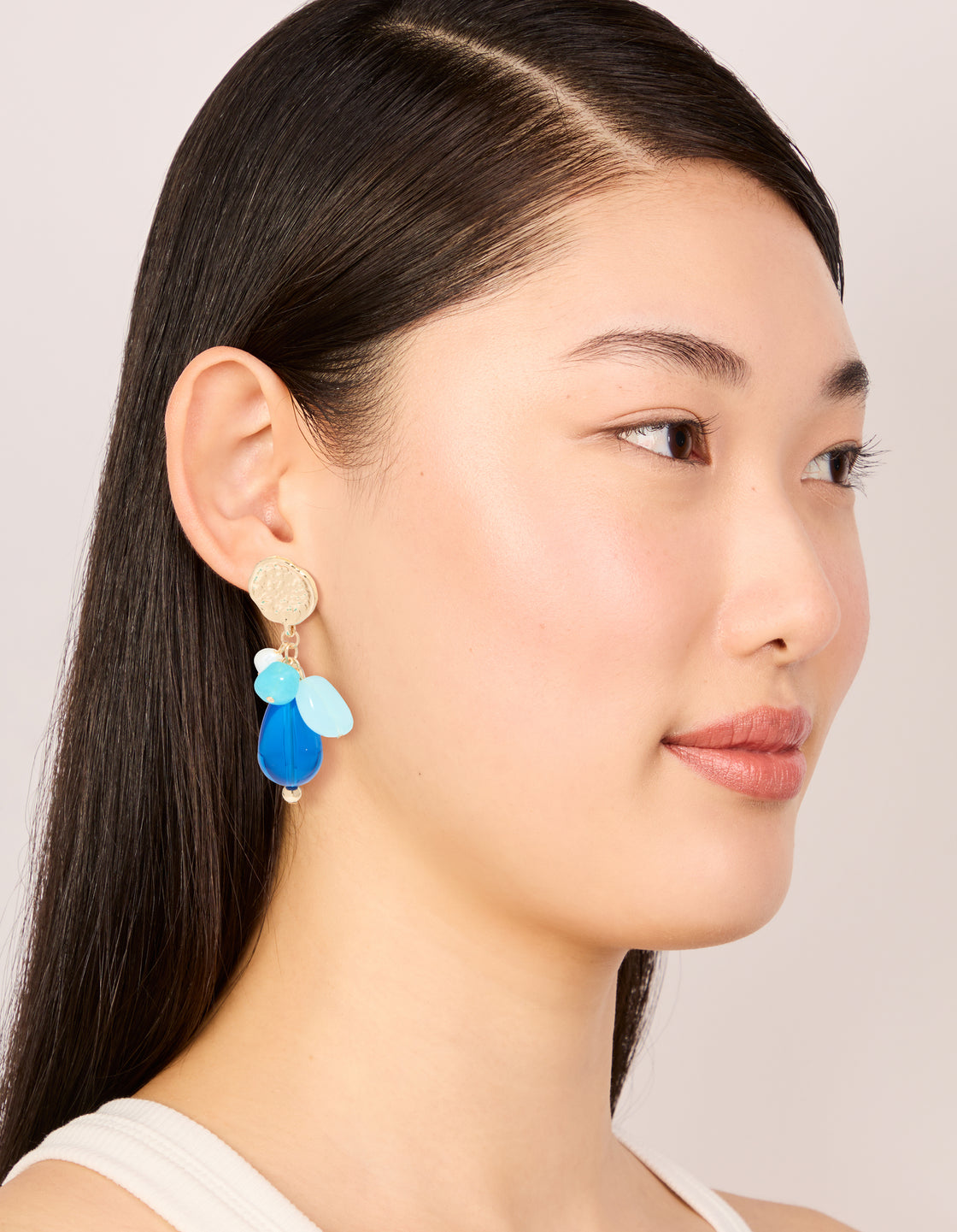 Featuring gold textured and blue beaded drop earrings with coin in statement style on model view