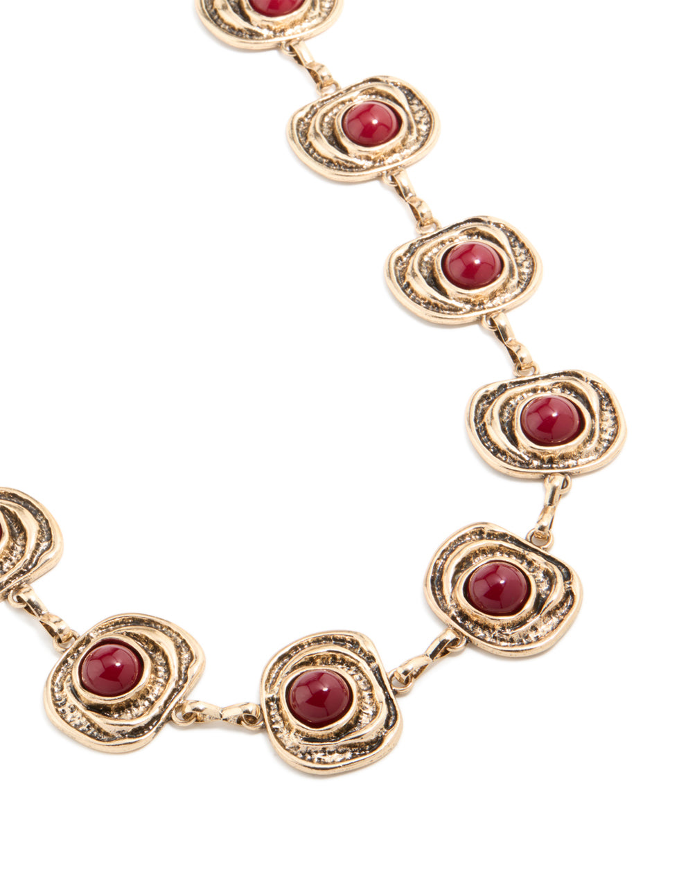 Showcasing an antique gold organic circle belt featuring dark red stones and an embellished pattern in a bold statement style detail view