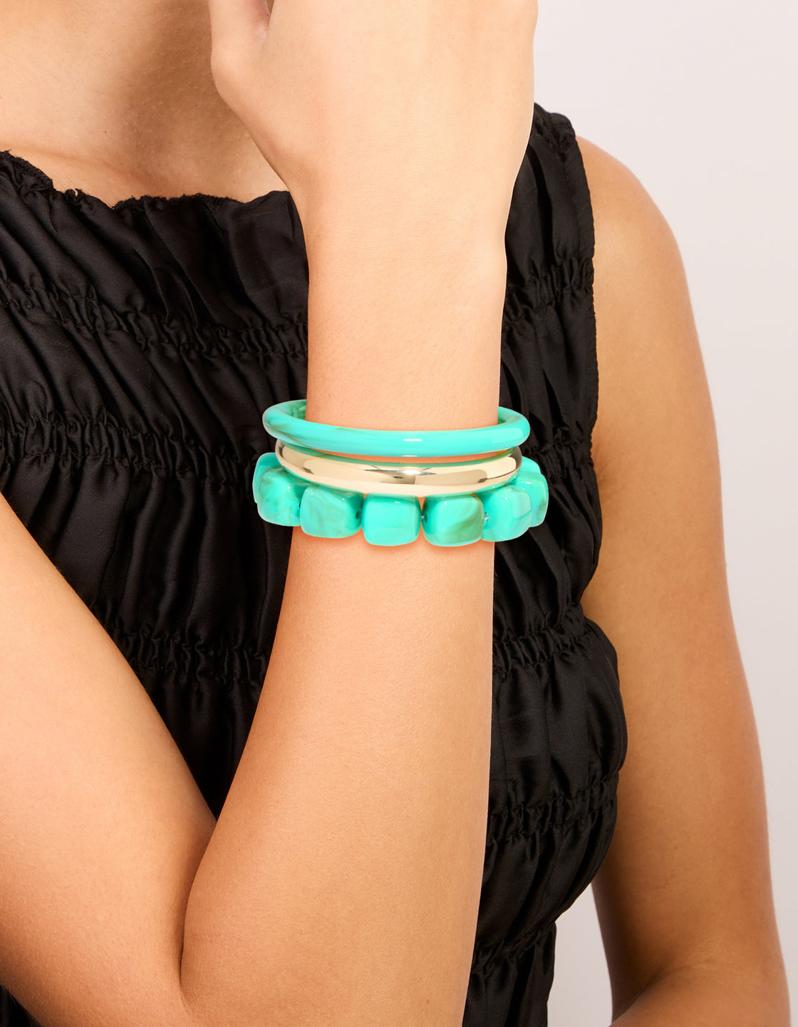 Showcasing gold and turquoise acrylic bracelets in a 3-pack with beaded bangle styles on wrist view