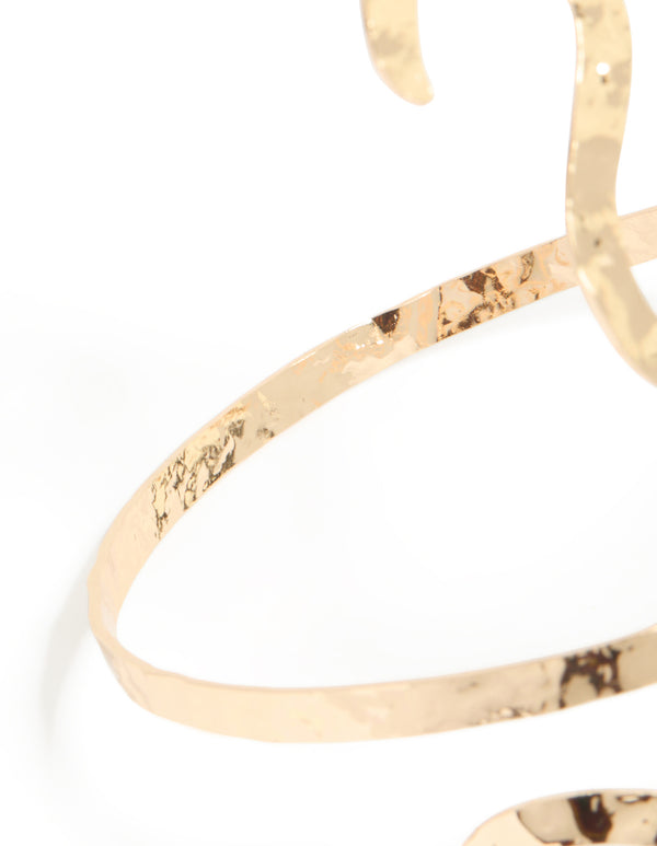 Showcasing the snake swirl arm cuff with hammered texture detail in statement gold detail view