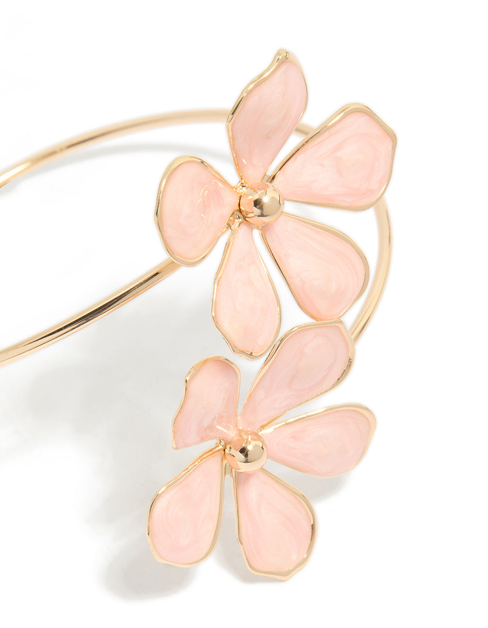 Crafted from enamel, this statement arm cuff with light pink floral design in gold close up view