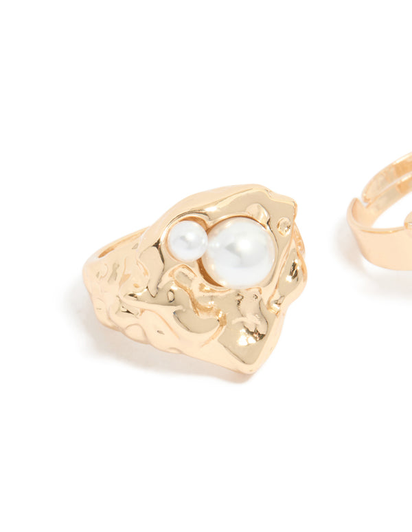 Close-up of brushed gold ring with pearl embellishment and ornate band design detail view