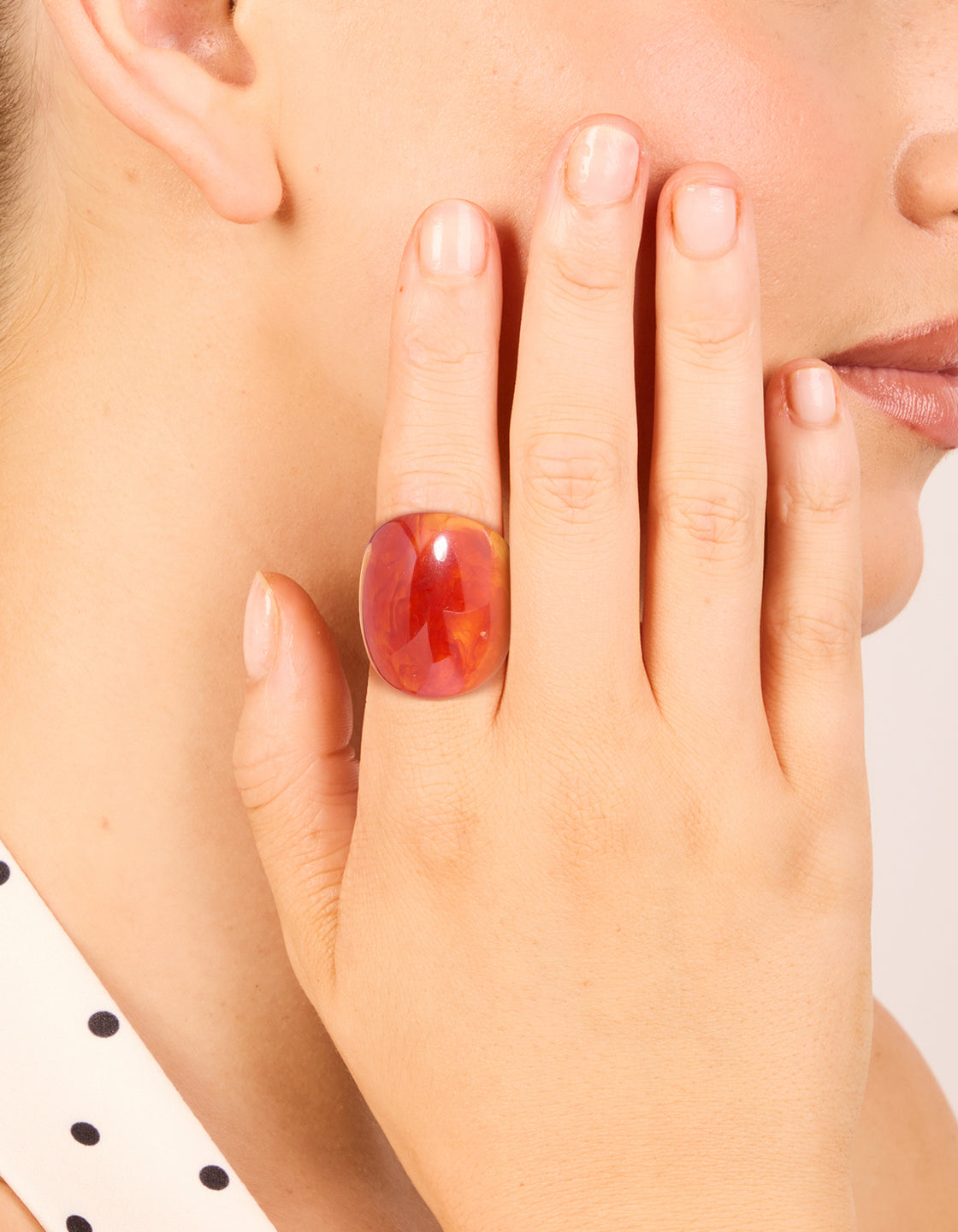 Showcasing statement acrylic rings in coral and orange with floral gold accents, 3-pack on finger view