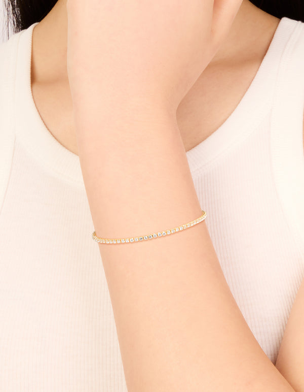 Showcasing a dainty gold plated cubic zirconia mini tennis toggle bracelet on wrist view