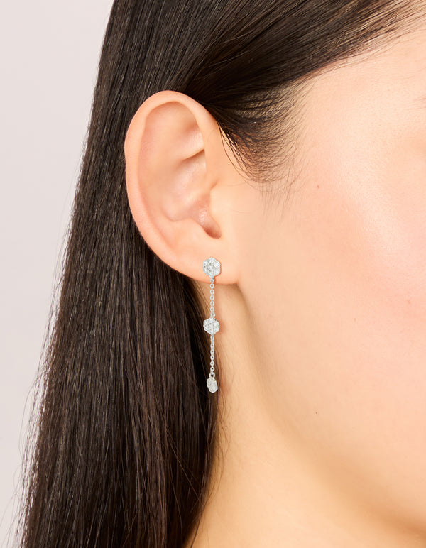 Showcasing silver cubic zirconia mini floral drop earrings with delicate chain design on ear view