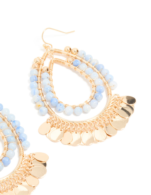 Highlighting statement teardrop earrings crafted with blue beads and gold disc layered elements post detail view