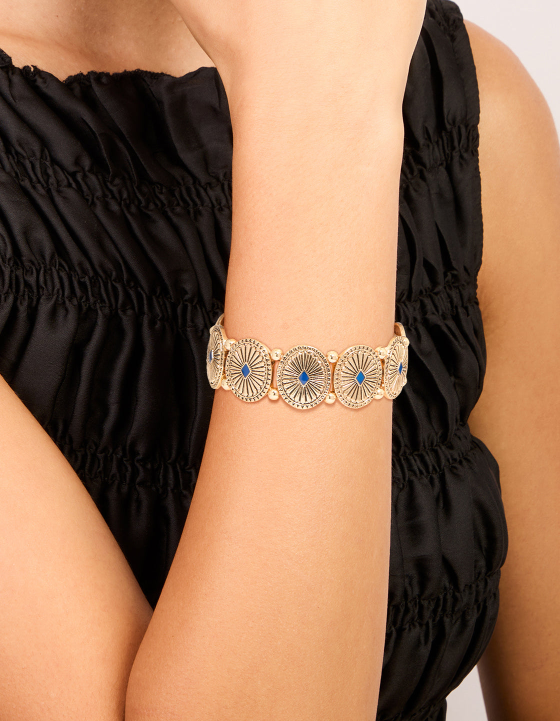 Showcasing an antique gold blue oval disc boho stretch bracelet with light sky blue accents on wrist view