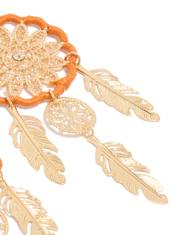 Detailed perspective of statement dreamcatcher earrings highlighting gold feathers with orange yarn and charm post detail view
