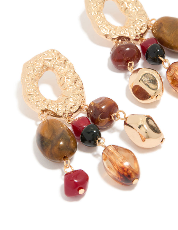 Crafted with irregular beaded drops, these earrings showcase charm details and statement design in gold close up view