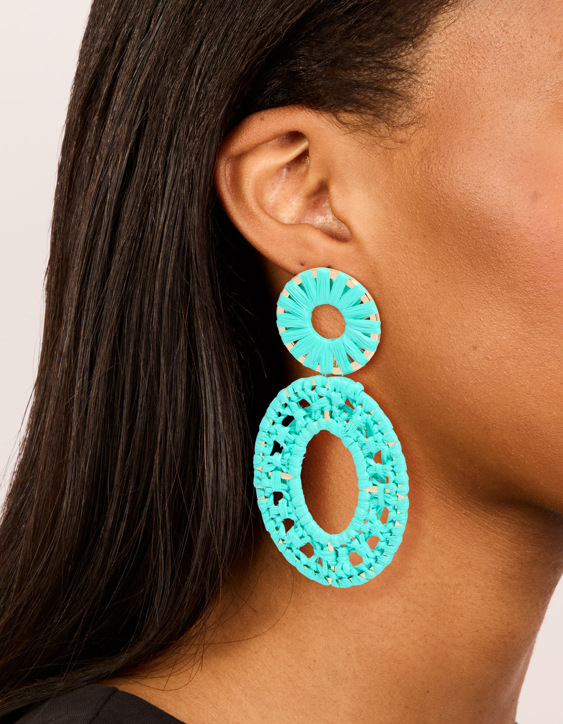 Showcasing aqua blue paper patterned oval drop earrings with statement style and gold accents on ear view