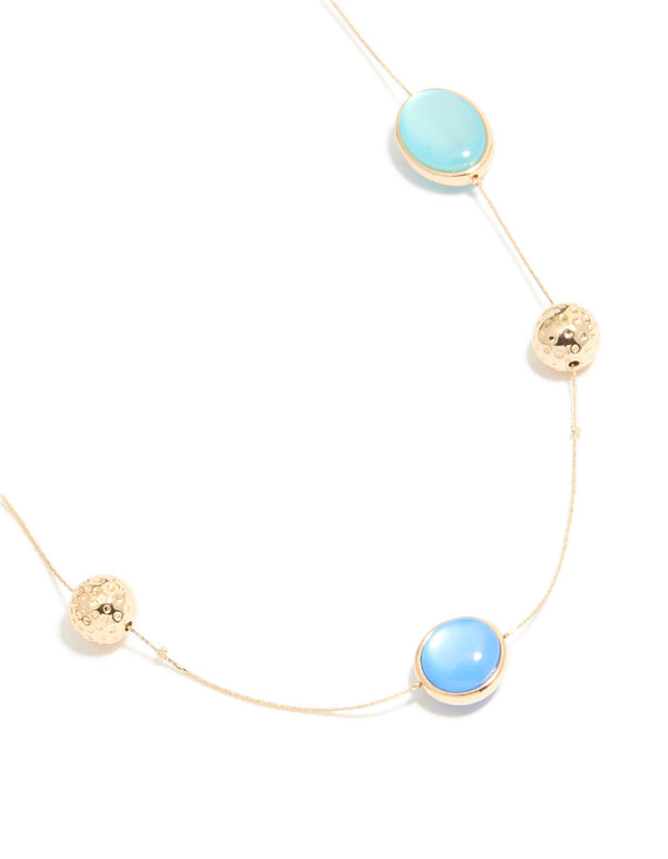 Featuring a gold long blue beaded necklace with textured balls and statement style close up view