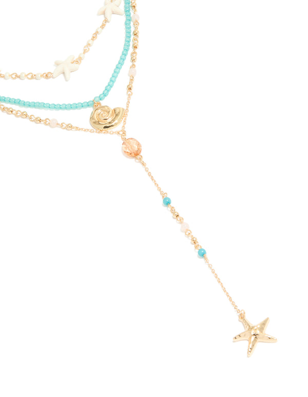 Crafted with blue beads and ivory accents, this gold shell and starfish layered Y-necklace features ocean-inspired features close up view