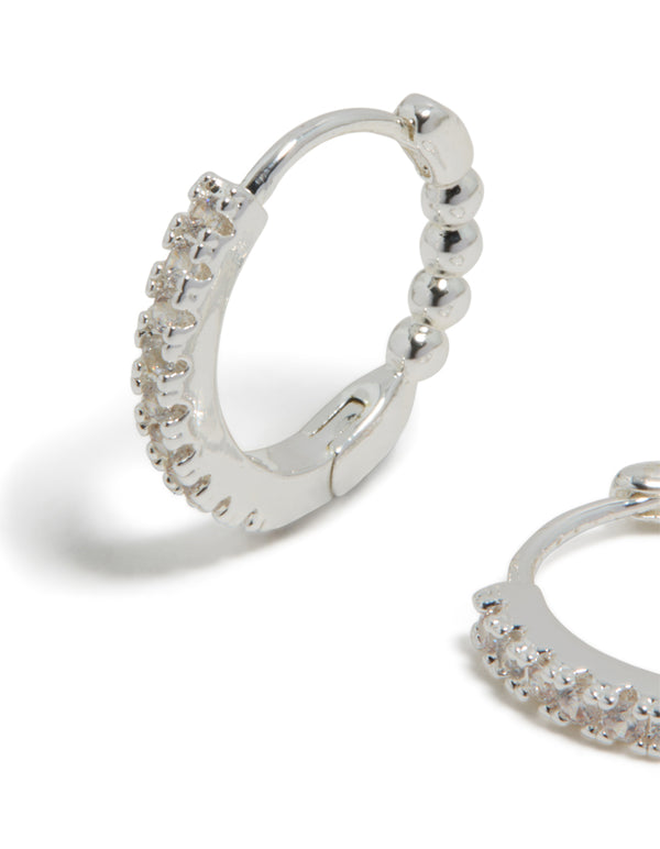 Featuring skinny huggie earrings in silver plated finish with cubic zirconia hoop closure close up view