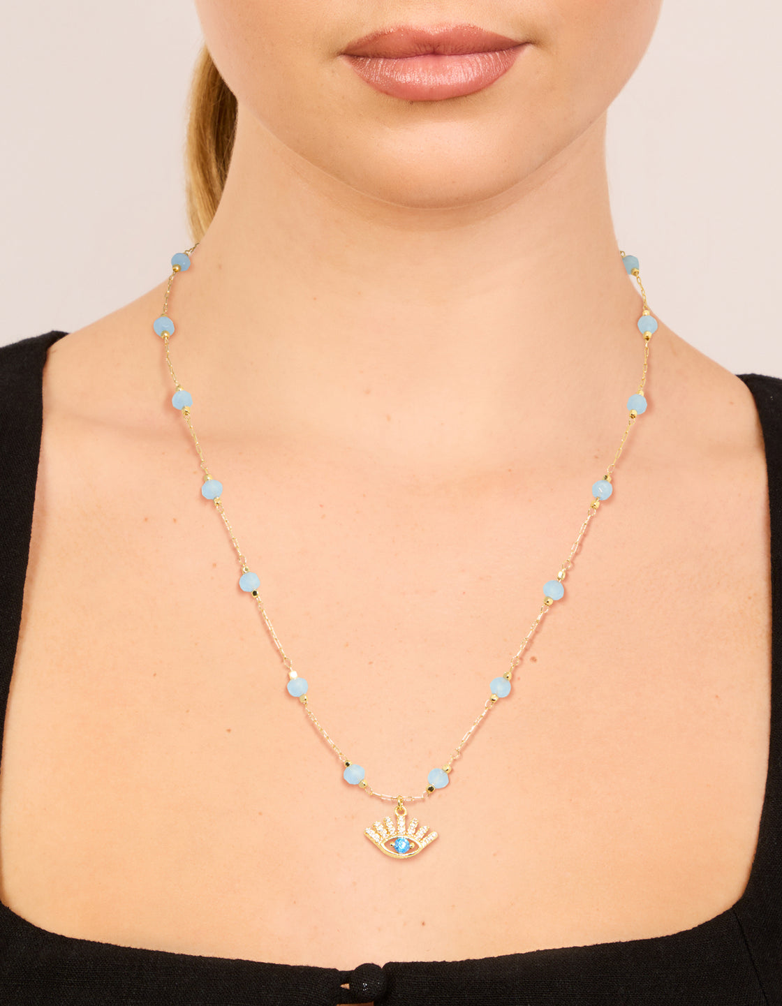 Showcasing a gold plated blue beaded and evil eye pendant necklace with cubic zirconia in a statement style on neck view