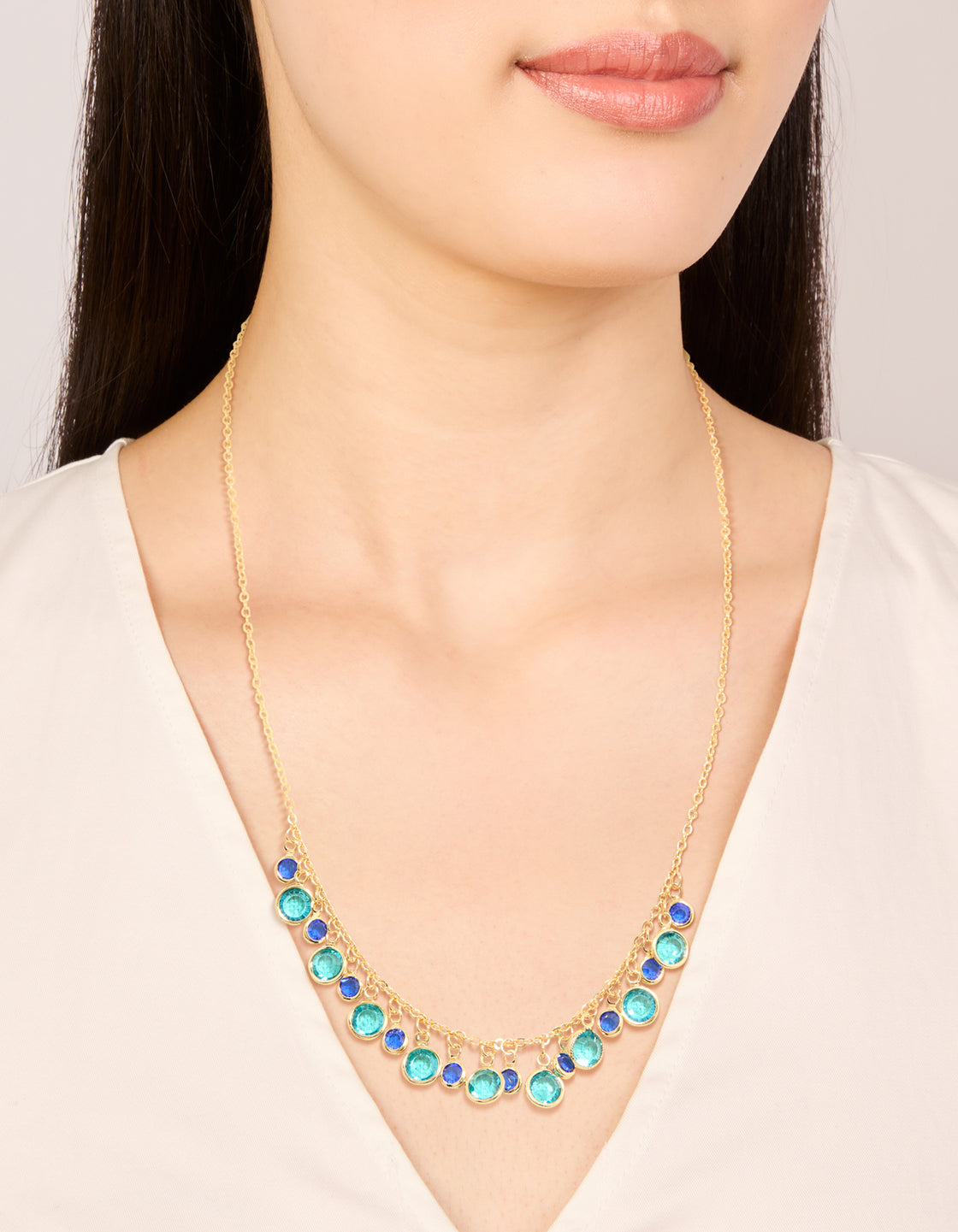 Showcasing a gold plated light and dark blue cubic zirconia circle necklace with statement design on neck view