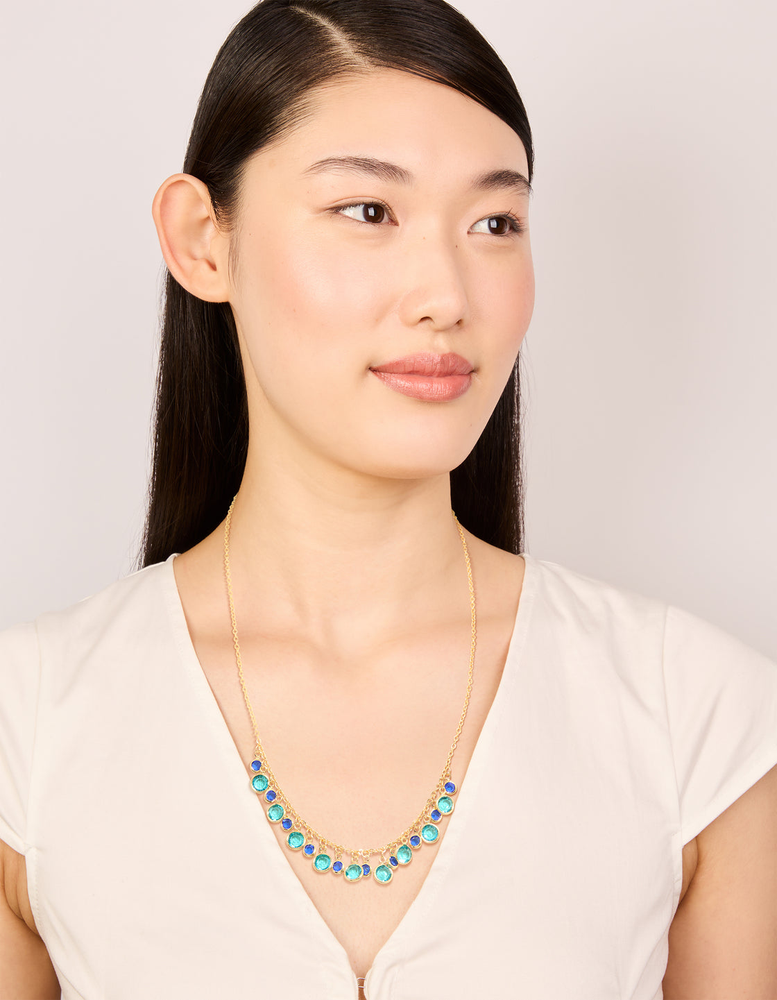 Crafted from gold plated material, this light and dark blue cubic zirconia circle necklace with statement design on model view