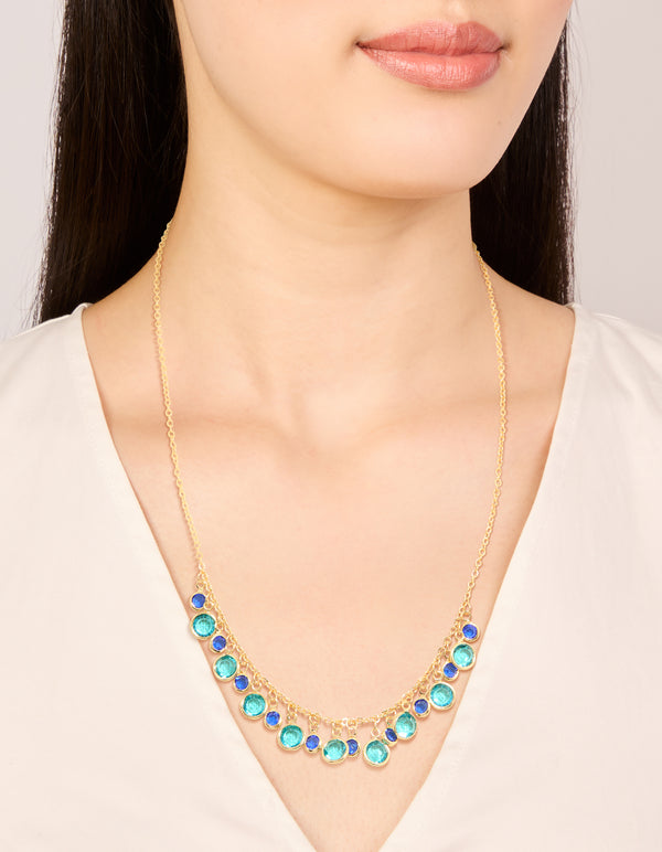 Showcasing a gold plated light and dark blue cubic zirconia circle necklace with statement design on neck view