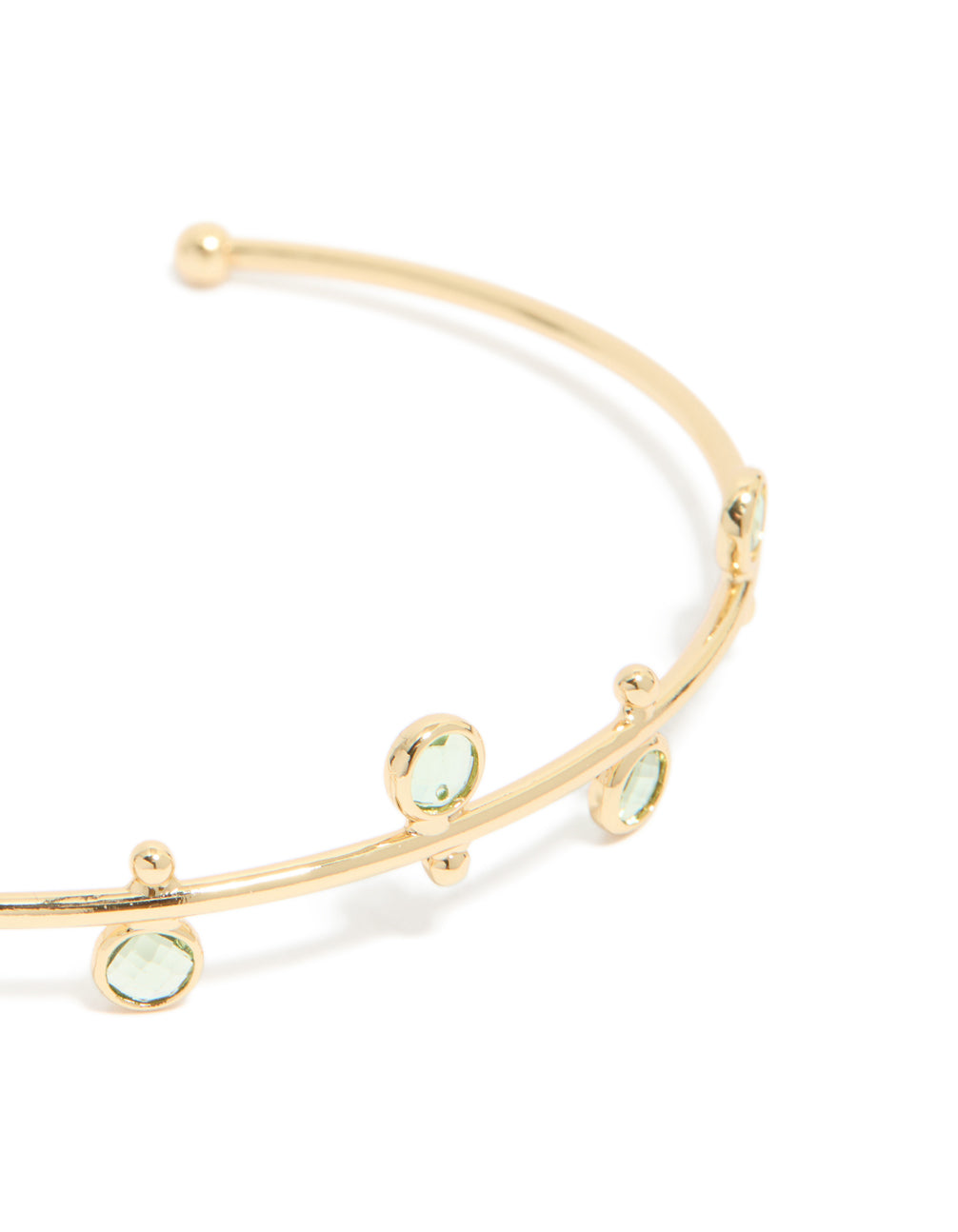 Featuring a gold plated and green cubic zirconia wrist cuff in a statement style, close up view