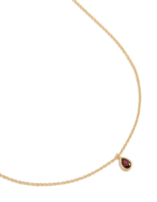 Showcasing a gold plated July birthstone necklace featuring a cubic zirconia pendant in a dainty statement style, close up view