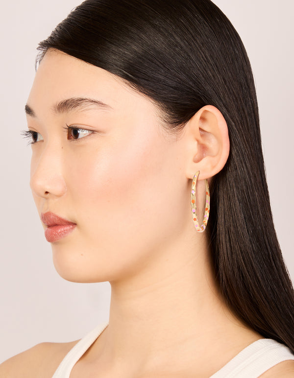 Designed with large statement hoop earrings featuring enamel dotted pattern in pink and orange on thin closure on model view