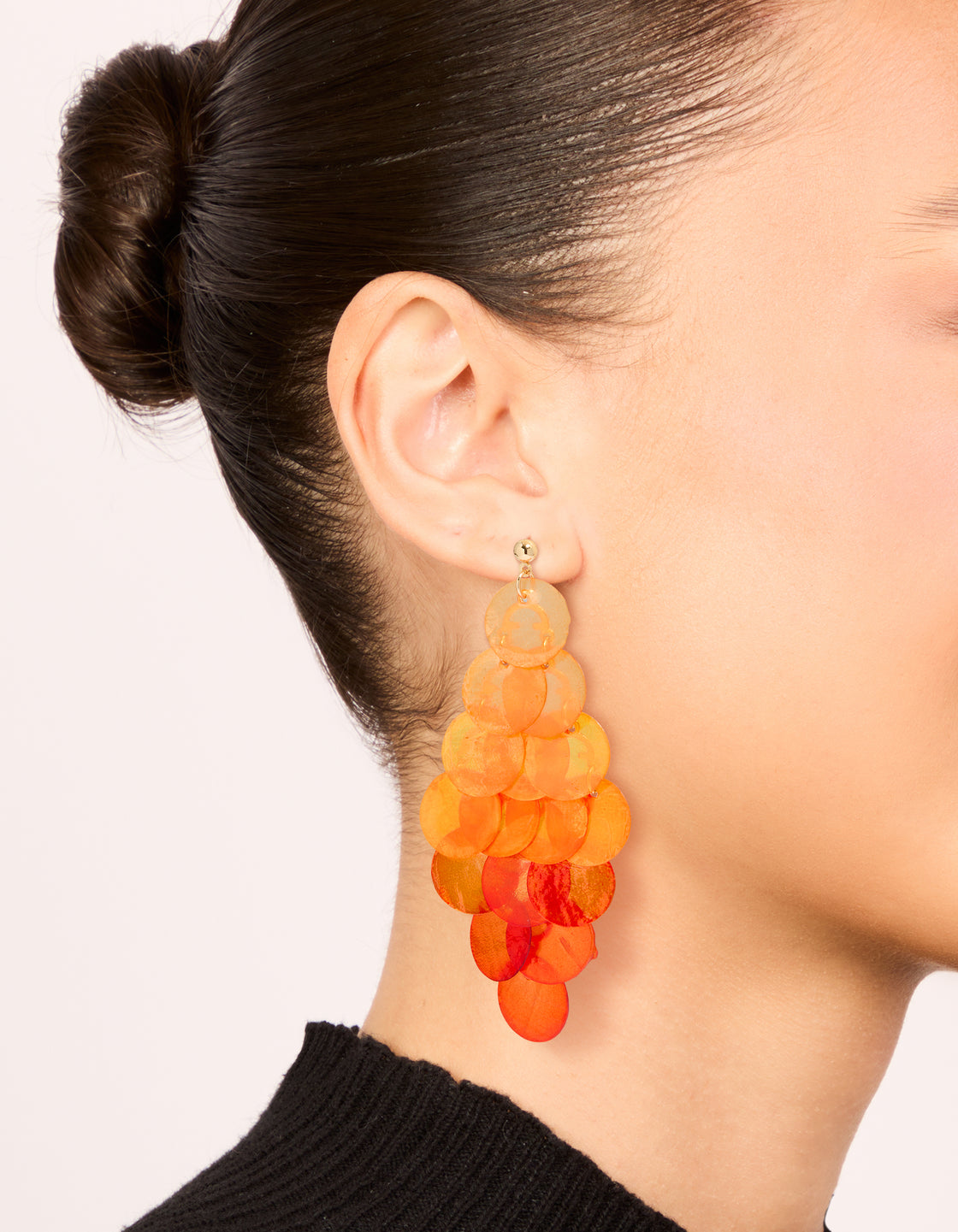 Crafted from genuine orange shell, these layered disc waterfall drop earrings feature statement styling in coral and peachpuff hues on ear view