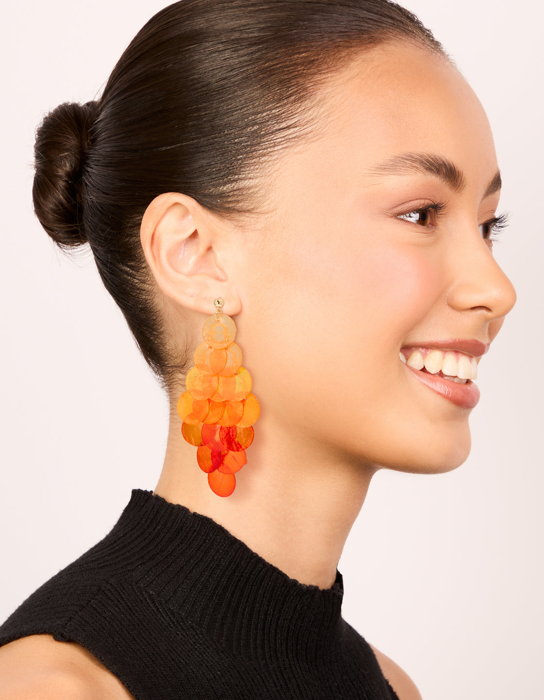 Designed with orange genuine shell layered discs, these waterfall drop earrings showcase statement style in coral and peachpuff colors on model view