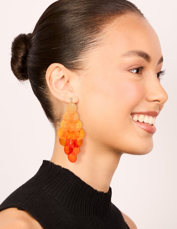 Designed with orange genuine shell layered discs, these waterfall drop earrings showcase statement style in coral and peachpuff colors on model view