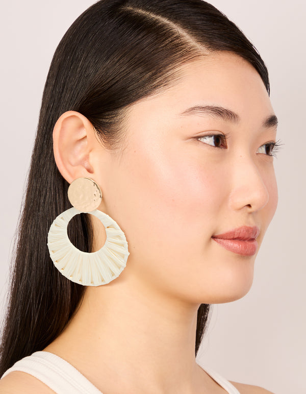Designed with textured raffia paper circles in white and hammered gold studs, statement drop earrings on model view